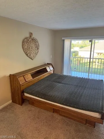 Carpeted bedroom with access to outside and a textured ceiling