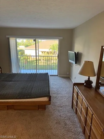 Carpeted bedroom with access to outside and a textured ceiling