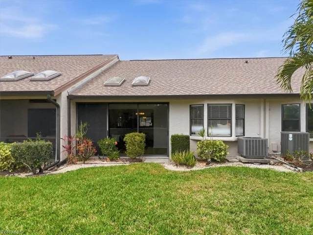View of front of home featuring a shingled roof, stucco siding, and a front yard