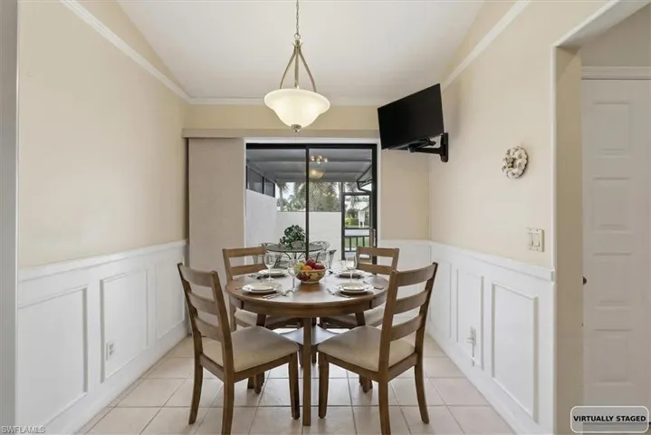Dining room with ornamental molding, wainscoting, and a decorative wall