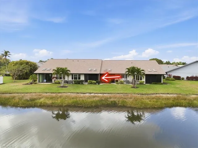 Rear view of property featuring a water view and a lawn