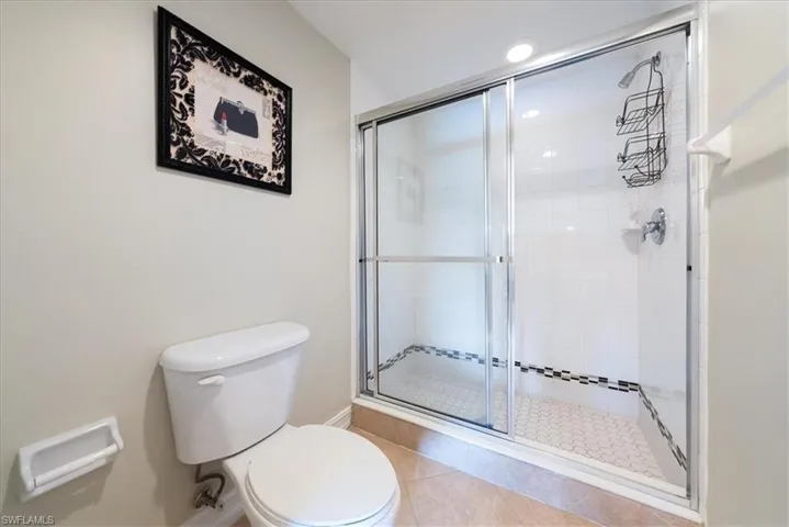 Bathroom featuring tile patterned flooring, toilet, and walk in shower