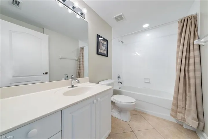 Full bathroom with tile patterned floors, toilet, shower / bath combo with shower curtain, and vanity