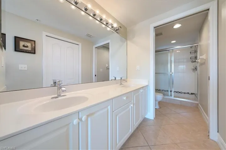 Bathroom with tile patterned flooring, vanity, a shower with shower door, and toilet
