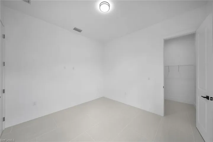 Unfurnished bedroom featuring a walk in closet and light tile patterned flooring