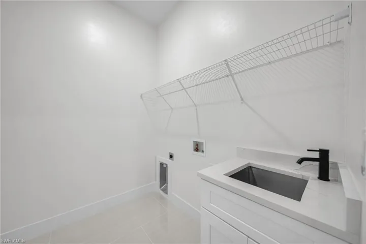 Laundry area with light tile patterned floors, hookup for a washing machine, electric dryer hookup, and cabinet space