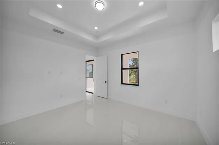 Spare room featuring a tray ceiling, recessed lighting, and light tile patterned floors