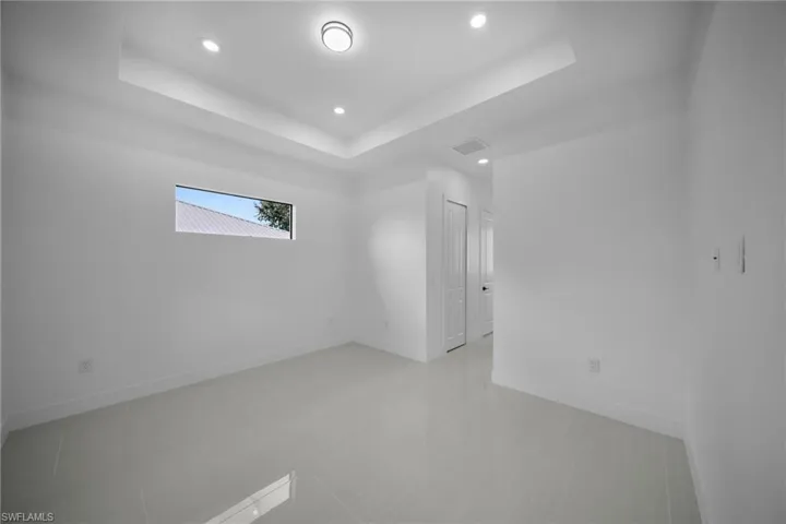 Unfurnished room featuring a raised ceiling, recessed lighting, and light tile patterned floors