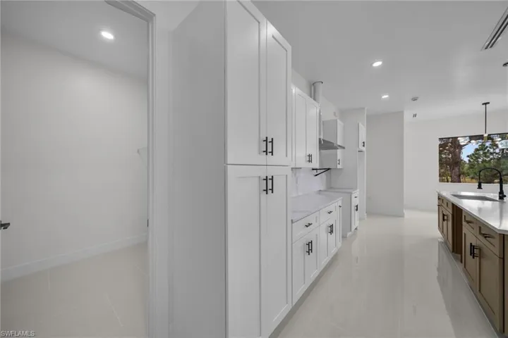 Kitchen featuring white cabinets, recessed lighting, decorative light fixtures, light tile patterned floors, and light stone countertops