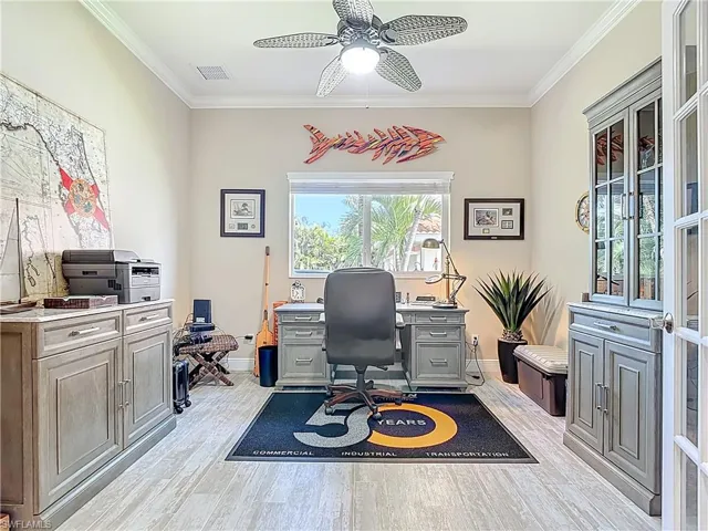 Office space featuring ornamental molding, light wood-style floors, and a ceiling fan