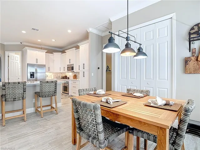 Dining area featuring crown molding, light wood finished floors, and recessed lighting