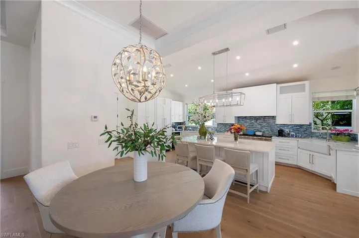 Dining space with an inviting chandelier, light wood flooring, and high ceiling