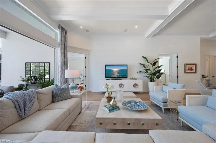 Living room with beamed ceiling, recessed lighting ,  sliding doors fully open to the lanai area.