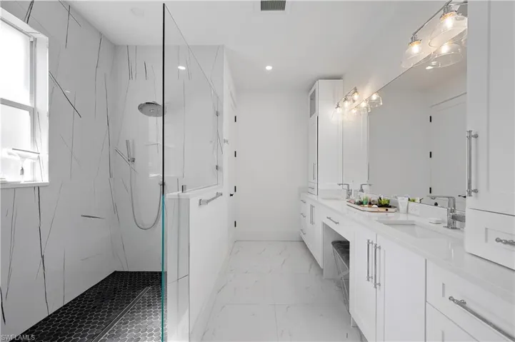 Bathroom with a marble finish shower, marble finish floor, double vanity, and a sink