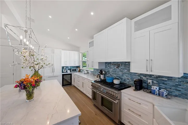 Kitchen featuring white cabinetry, double oven range, tasteful backsplash, and beverage cooler