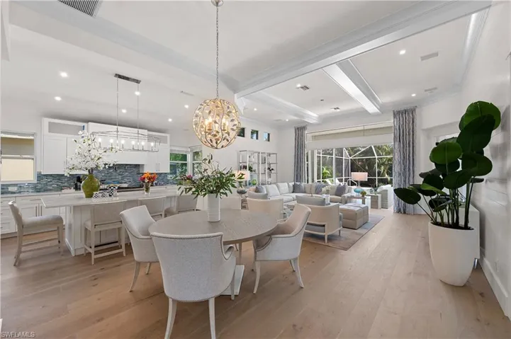 Dining area with beamed ceiling, recessed lighting, light hardwood floors.