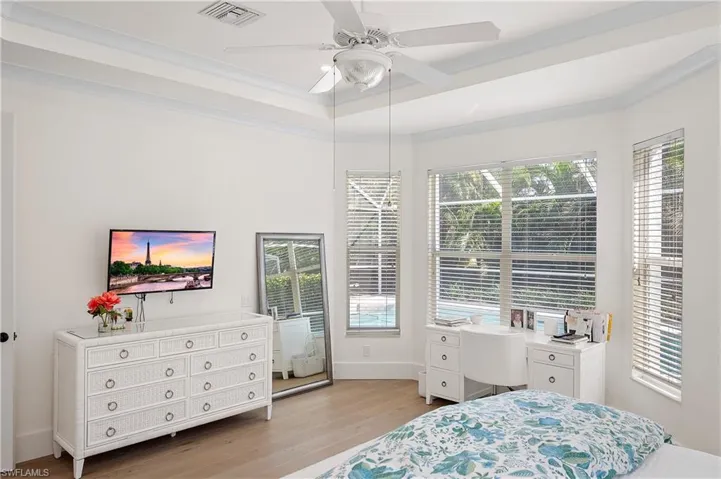 Bedroom with ceiling fan, light wood finished floors and view of the pool.