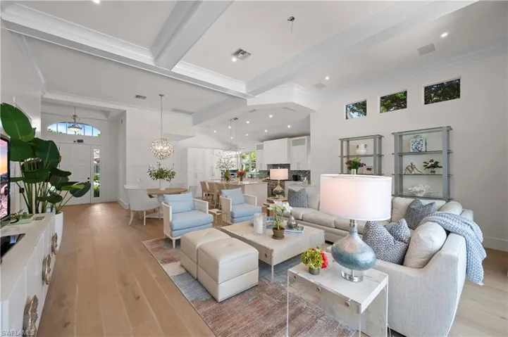 Living room featuring recessed lighting, an inviting chandelier, beamed ceiling, light wood flooring, and crown molding