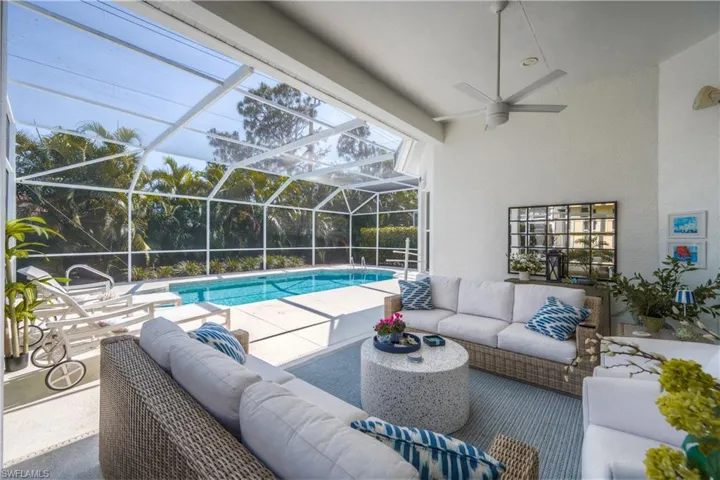 Outdoor pool featuring glass enclosure, a patio area, a covered outdoor area, and ceiling fan