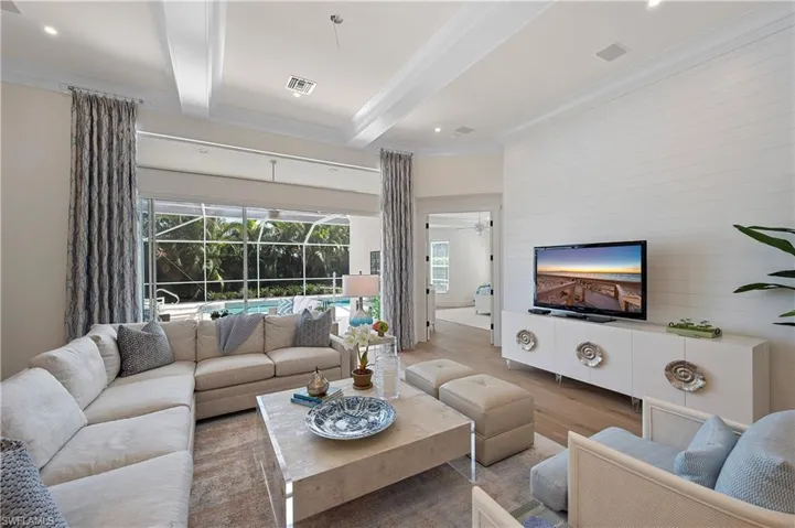 Living area featuring beam ceiling, a ceiling fan, visible vents, ornamental molding, and wood finished floors