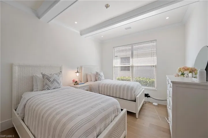 Bedroom featuring visible vents, light wood-type flooring, ornamental molding, and beamed ceiling