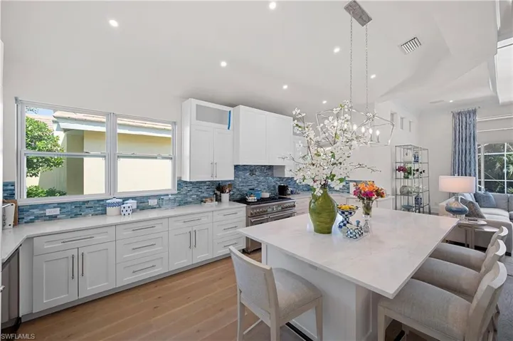 Kitchen with double gas oven range, a kitchen bar, decorative backsplash, and light wood floors