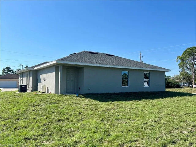 Rear view of house featuring a yard and central air condition unit