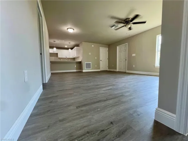 Unfurnished living room featuring ceiling fan, sink, and dark hardwood / wood-style flooring