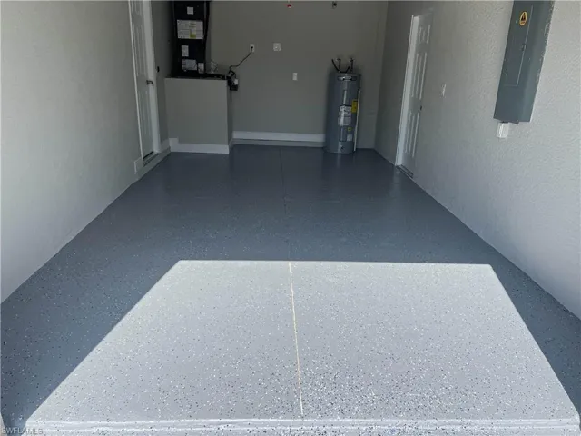 Garage featuring electric panel, electric water heater, and heating unit
