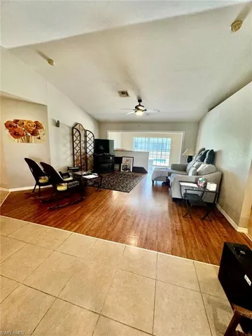 Living room featuring a textured ceiling, wood-type flooring, ceiling fan, and vaulted ceiling
