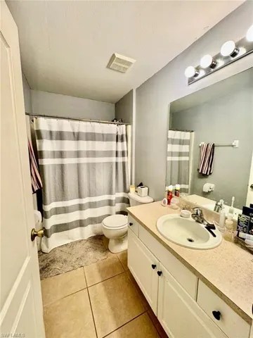 Bathroom with tile flooring, large vanity, and toilet