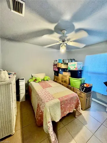 Bedroom featuring tile floors, a textured ceiling, and ceiling fan