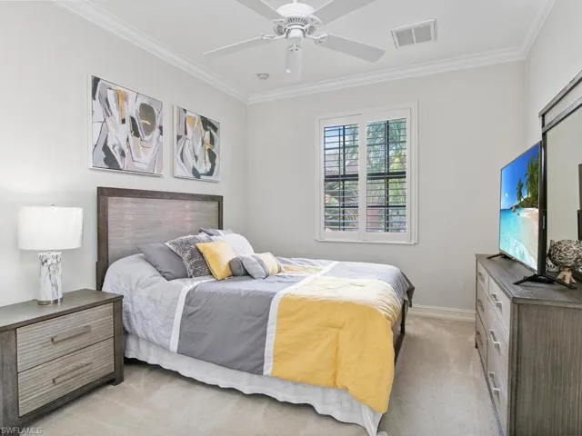 Bedroom featuring light carpet, ornamental molding, and a ceiling fan