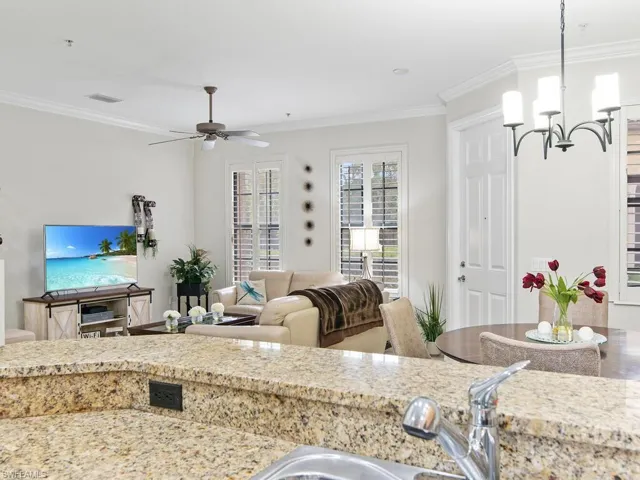 Kitchen featuring ornamental molding, ceiling fan, a chandelier, light stone countertops, and decorative light fixtures