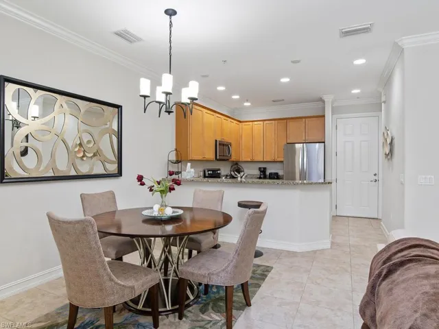 Dining room with ornamental molding, light tile patterned flooring, a chandelier, and recessed lighting