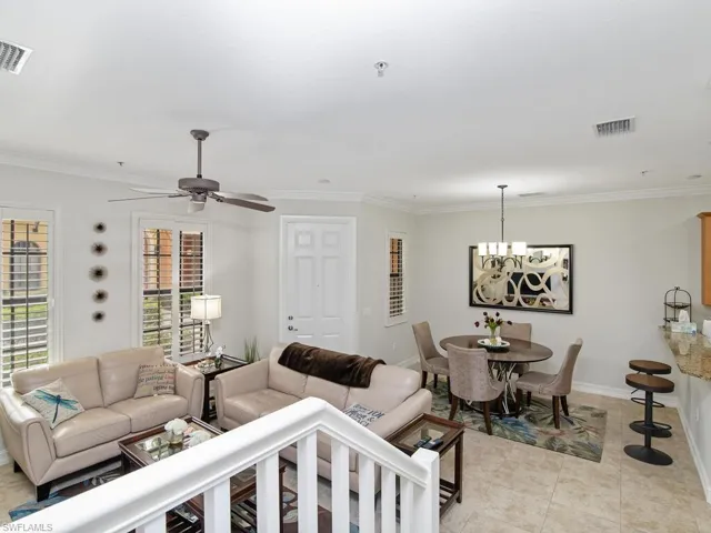 Living area featuring a chandelier, ornamental molding, a ceiling fan, and light tile patterned floors