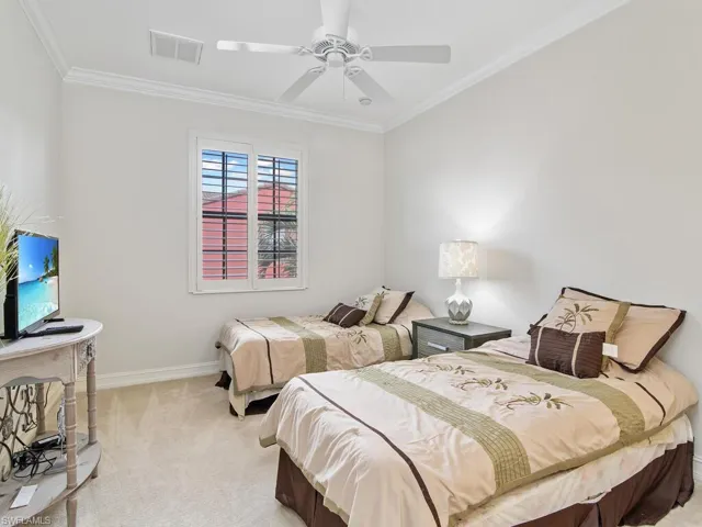 Bedroom with light colored carpet, ornamental molding, and a ceiling fan
