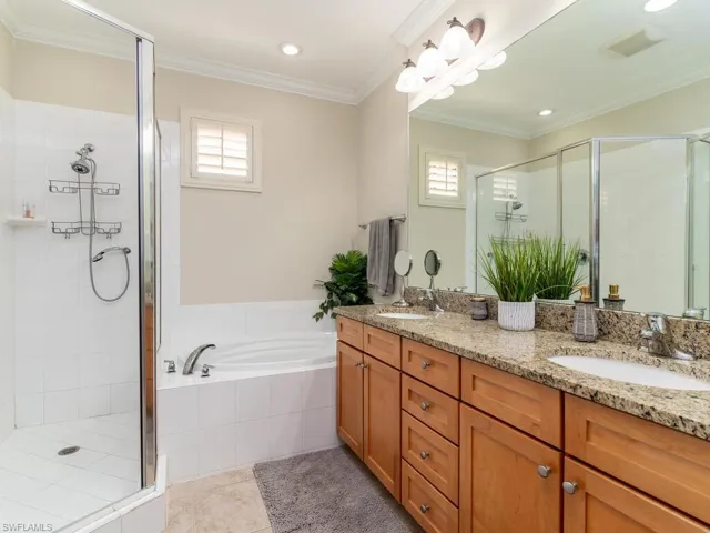 Bathroom featuring double vanity, a stall shower, a garden tub, healthy amount of natural light, and ornamental molding