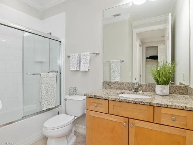 Full bathroom featuring vanity, enclosed tub / shower combo, and crown molding