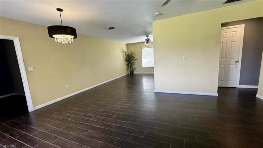 Open-concept interior featuring wood-finish tile flooring, a multi-tiered drum chandelier with crystal detailing, a ceiling fan, and multi-panel doors