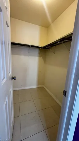 Storage space featuring tile flooring and built-in shelving with bracket support