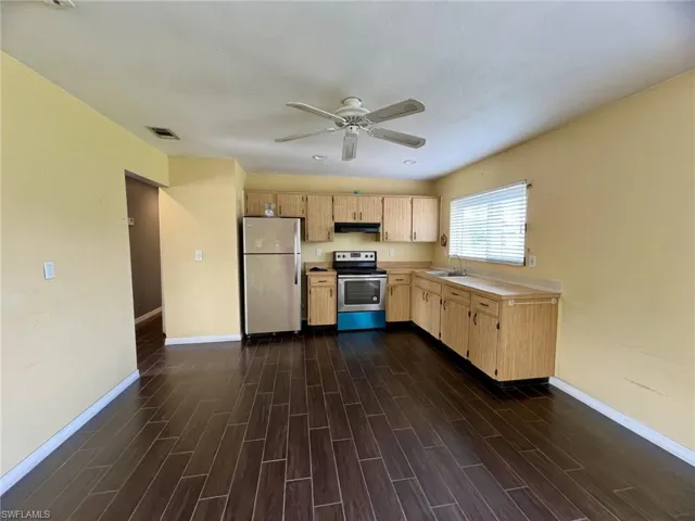 Kitchen featuring wood-finish flooring, stainless steel refrigerator, electric range with integrated vent hood, and natural wood cabinetry