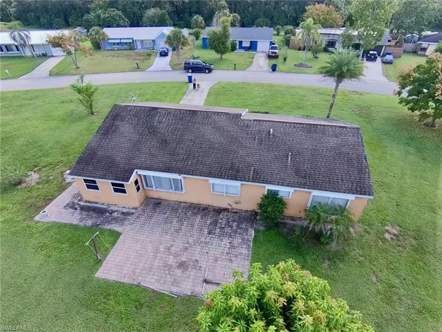 Single-story exterior featuring a shingle roof, paved patio, and expansive lawn