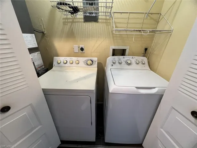 Dedicated laundry area featuring dual white top-load appliances, louvered closet doors, and wall-mounted wire shelving