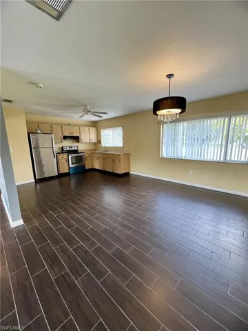 Wood-finish tile flooring throughout, stainless steel kitchen appliances, wood-finish cabinetry, and a crystal-accented drum pendant light fixture