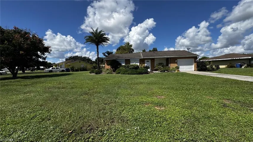 Single-story residence featuring a brick exterior, shingled roof, attached one-car garage, concrete driveway, and expansive lawn