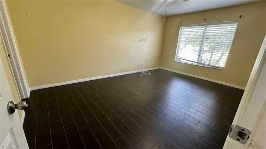 Wood-finish flooring with a horizontal plank layout, neutral wall color, and window with adjustable horizontal blinds