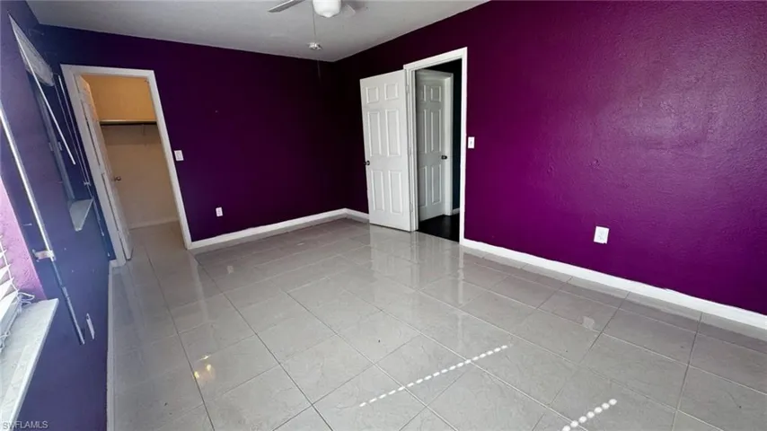 Large-format tile flooring, ceiling fan, and paneled interior doors