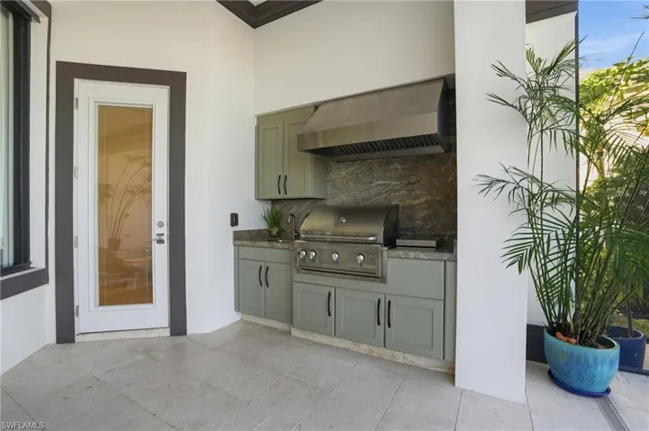 The summer kitchen features a gas grill and a hot plate with a sink and plenty of storage