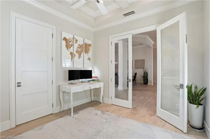 The spacious den features glass french doors and detailed crown molding on the ceilings